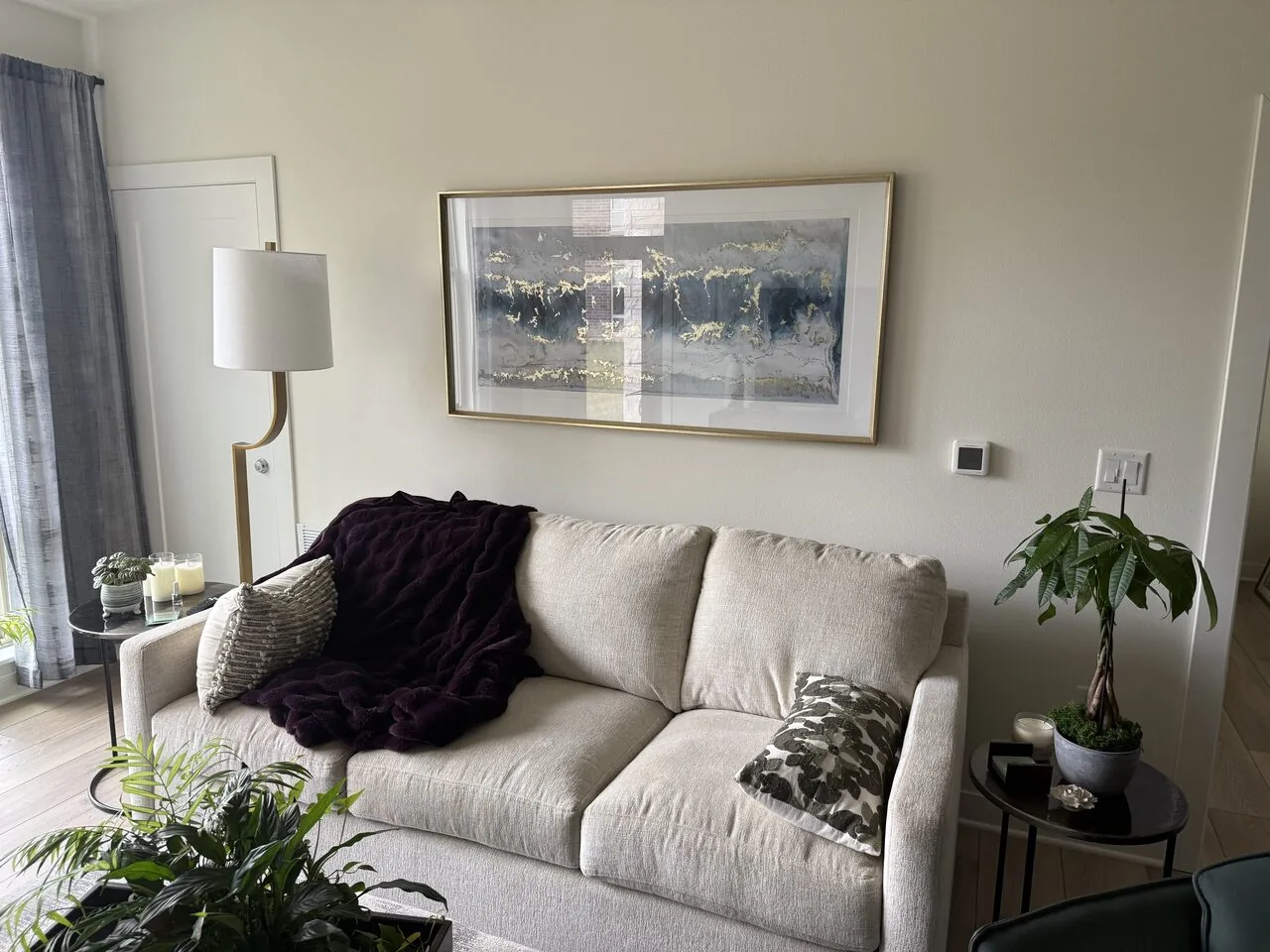 Large framed landscape print hung centered above a living-room sofa