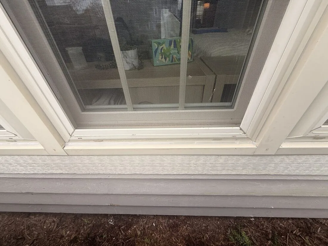 Exterior window sill freshly sealed and caulked above lap siding