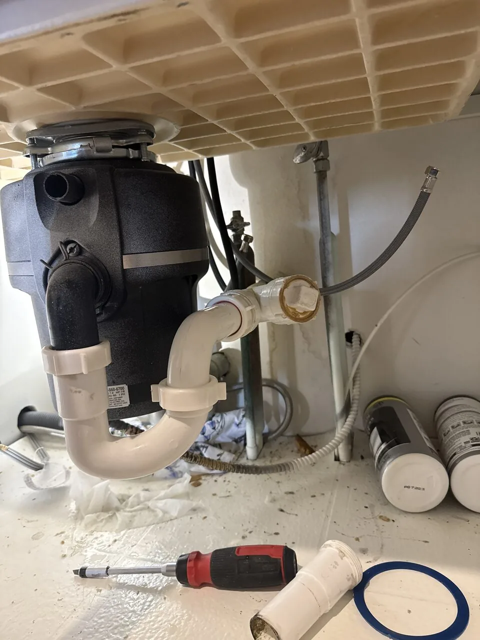 New garbage disposal installed under a kitchen sink with the P-trap and drain lines reconnected