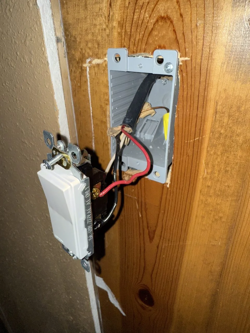 Wall switch wired to a new electrical box recessed into wood paneling
