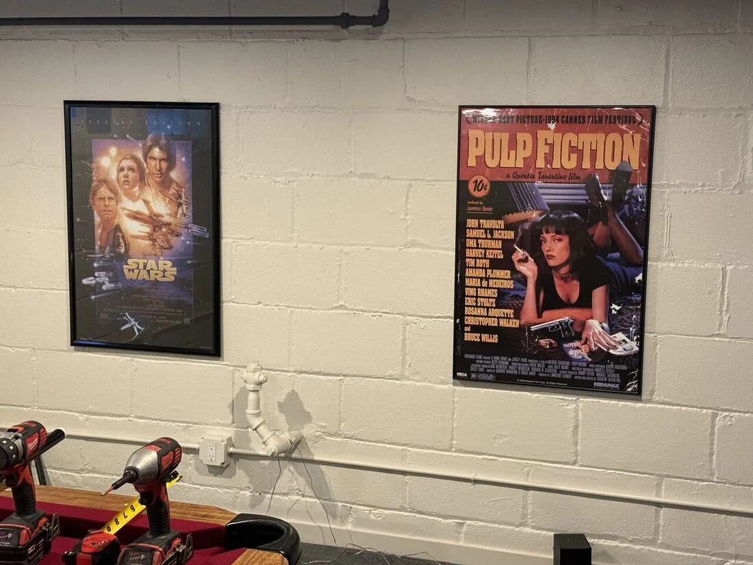 Framed movie posters mounted level on a basement block wall