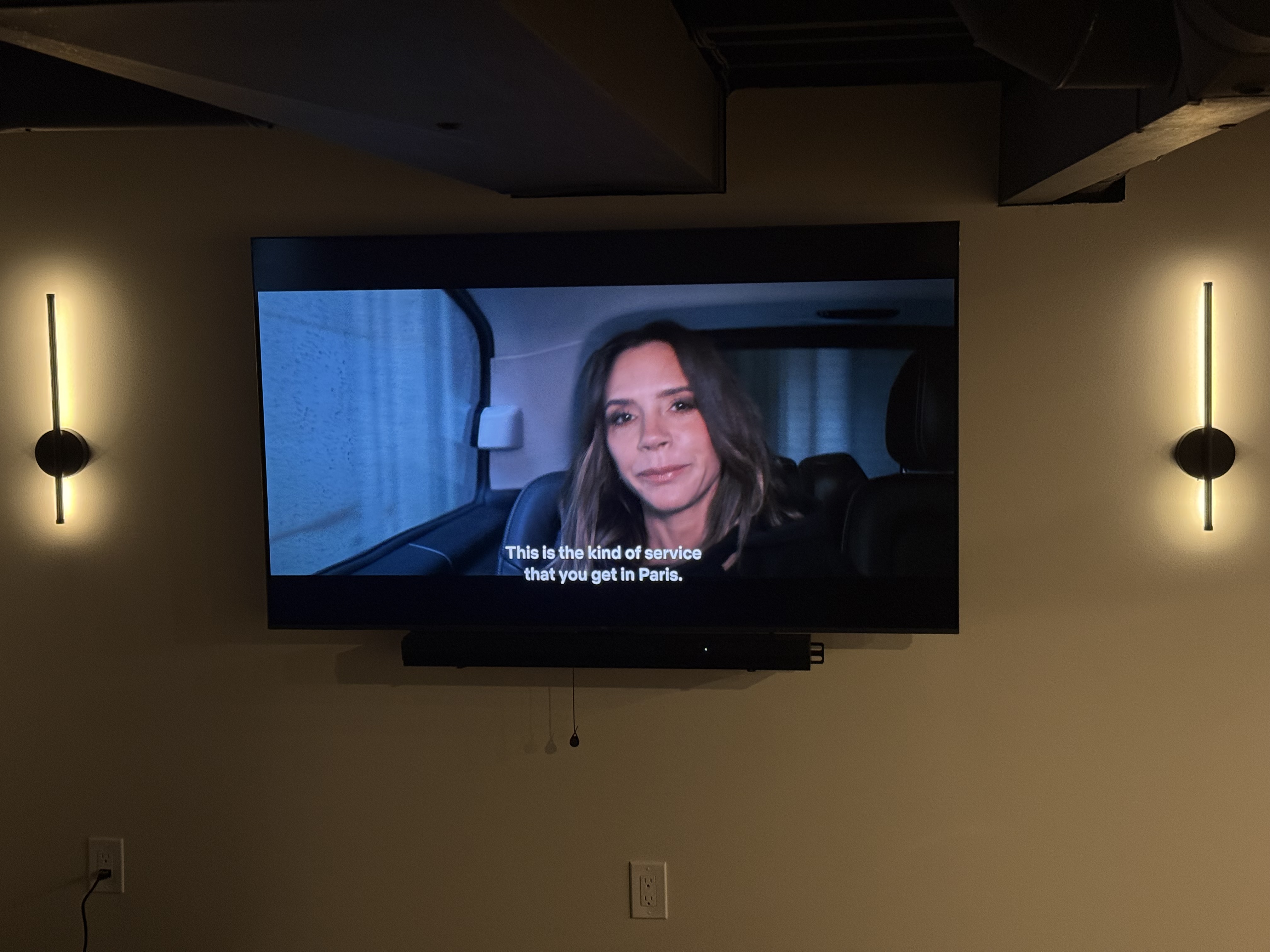 TV mounted on wall with wall sconces in basement home theater by North Shore Fixers Milwaukee